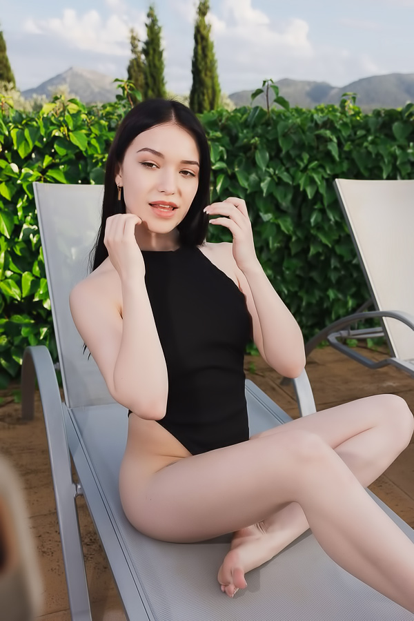 Wikki Kee solo by the pool in black bodysuit, teasing with a butt plug under sunny skies