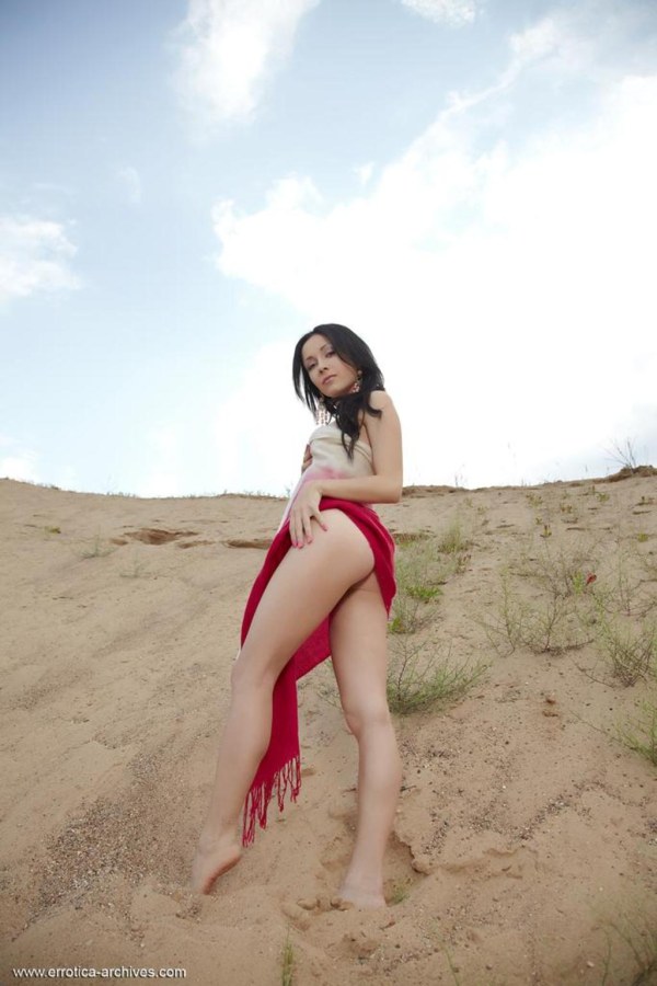 Lady in red poses in sand