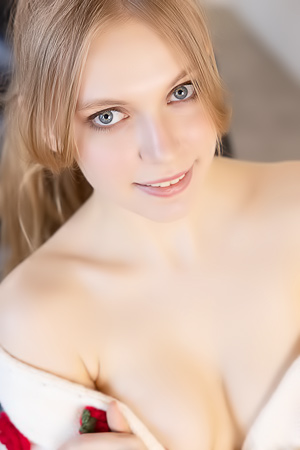 Sonya Elf teases in pink lingerie, topless on a black chair, posing solo with soft curves and confident gaze