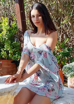 Ryanne Keena bares her curves on a sunlit stone bench, floral wrap slipping as she poses nude outdoors